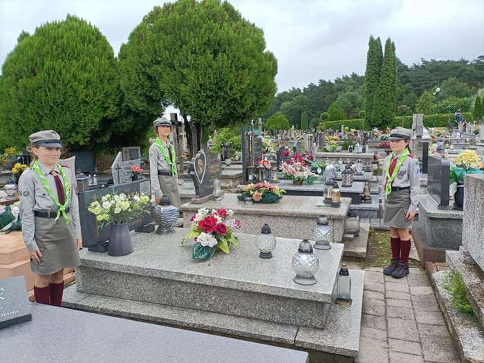 Trzy harcerki z Drużyny Harcerskiej SP11 Niewidzialne Dłonie przy grobie Stanisława Kolasy. Fot. DH SP 11 Niewidzialne Dłonie